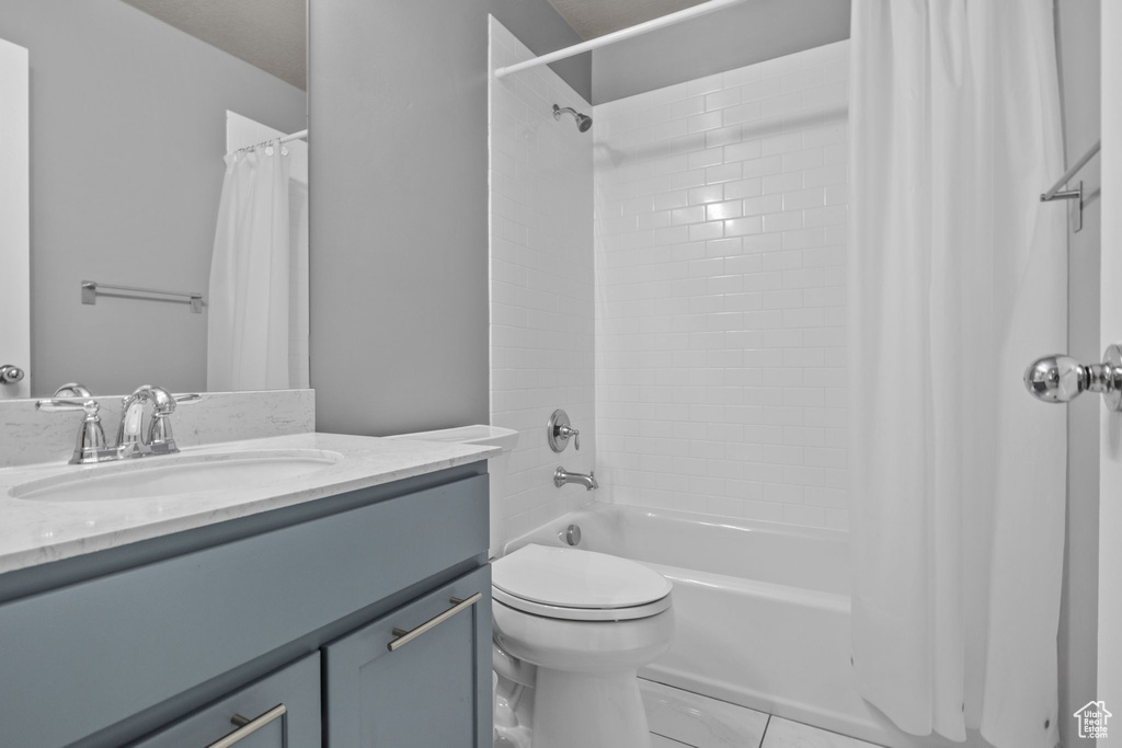 Full bathroom with vanity, shower / bath combo with shower curtain, toilet, and tile patterned floors