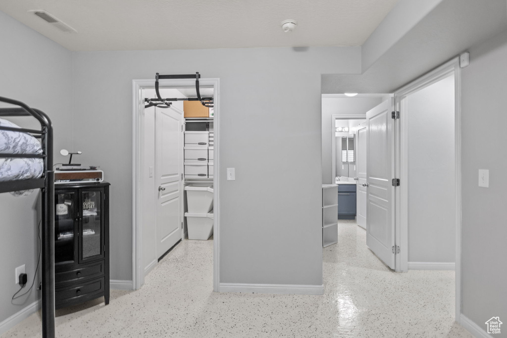 Bedroom featuring a walk in closet, baseboards, and ensuite bath