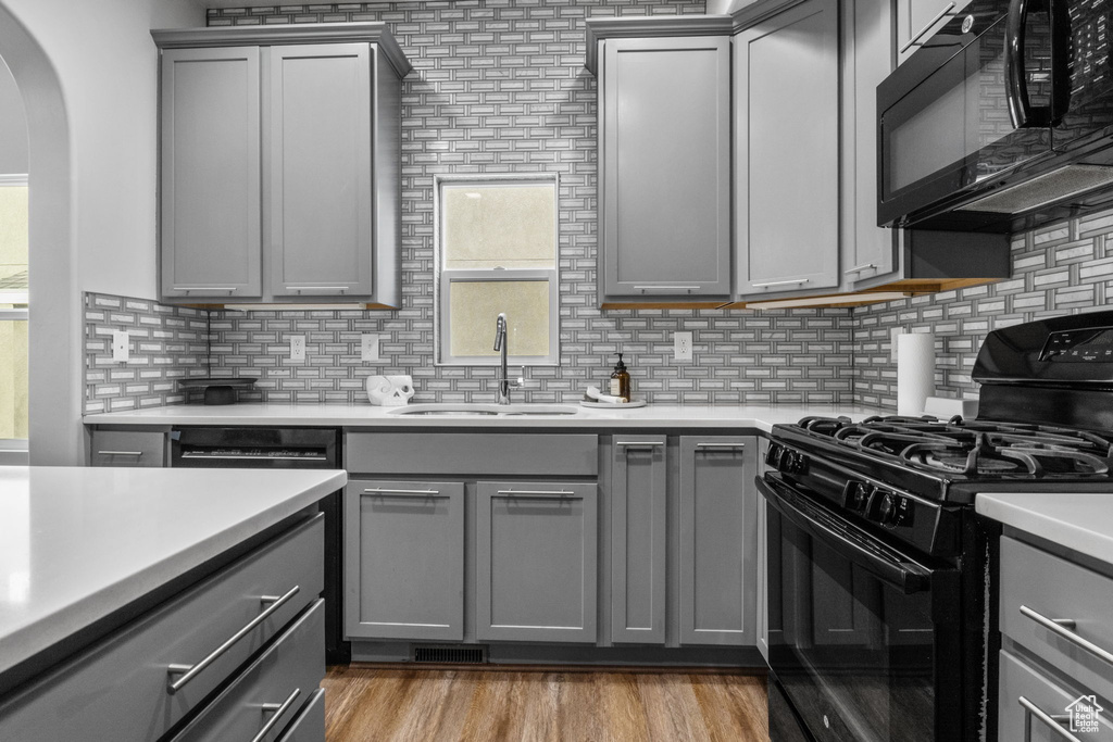 Kitchen featuring gray cabinetry, black appliances, a sink, and backsplash