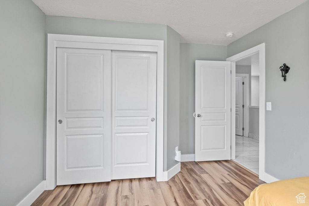 Unfurnished bedroom featuring a closet, baseboards, and light wood-type flooring