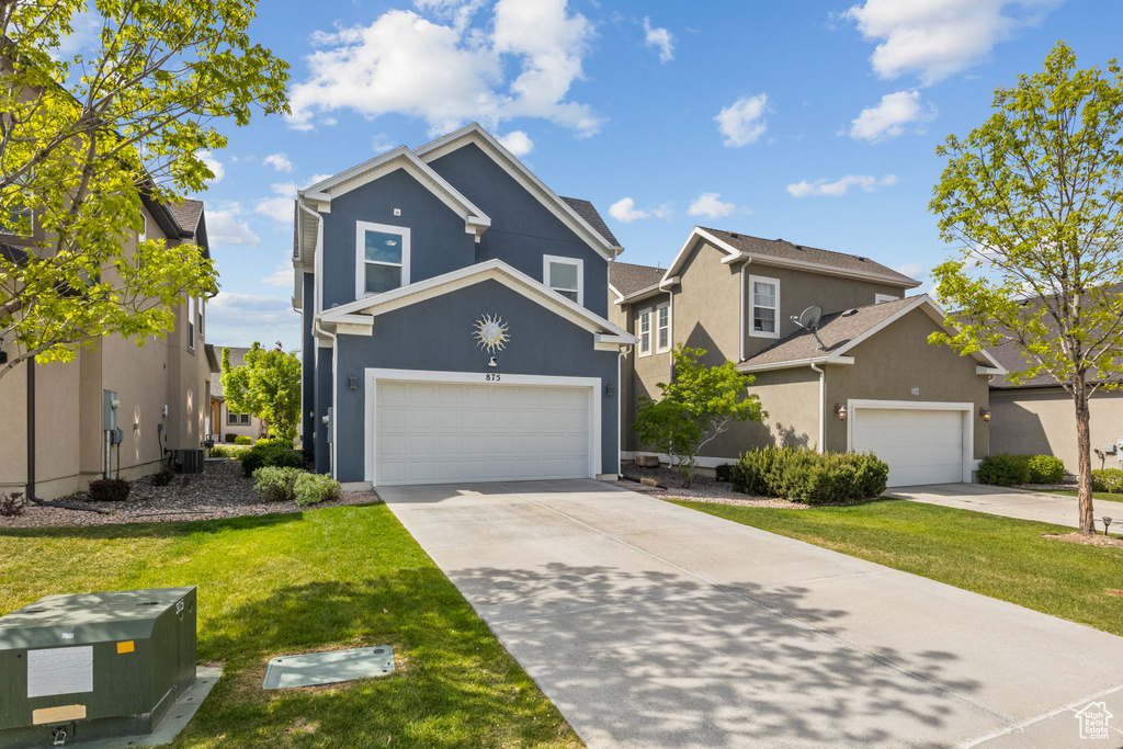 Traditional-style house with stucco siding, driveway, a front yard, central AC, and a residential view
