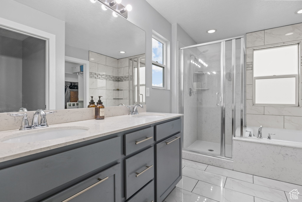 Full bath with marble finish floors, a stall shower, double vanity, a bath, and recessed lighting
