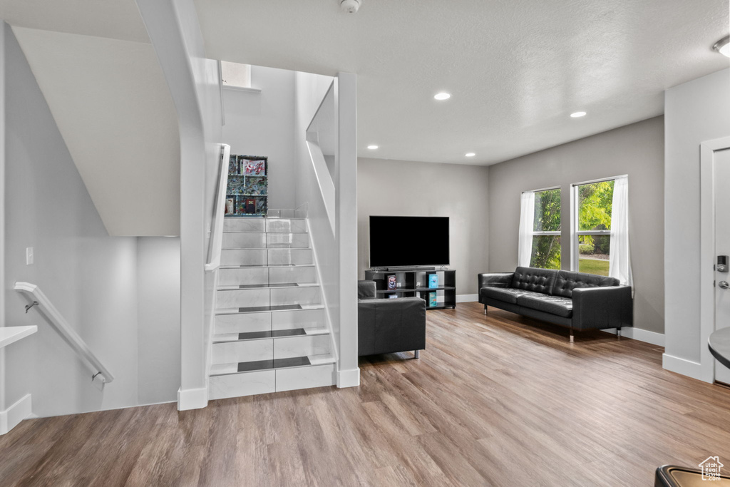Living area with wood finished floors, stairway, recessed lighting, and baseboards