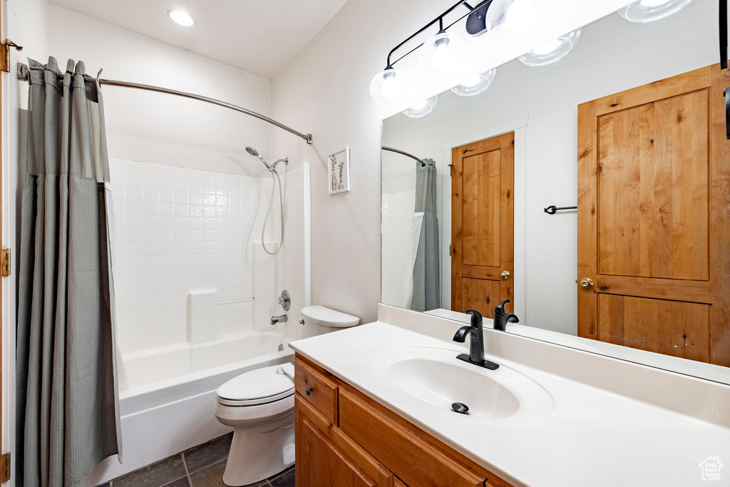 Full bath featuring toilet, vanity, shower / bath combo with shower curtain, and tile patterned flooring