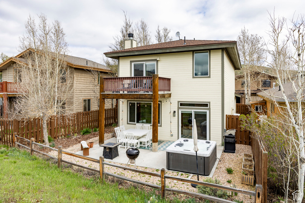 Rear view of property featuring a chimney, a fenced backyard, a patio, and a balcony