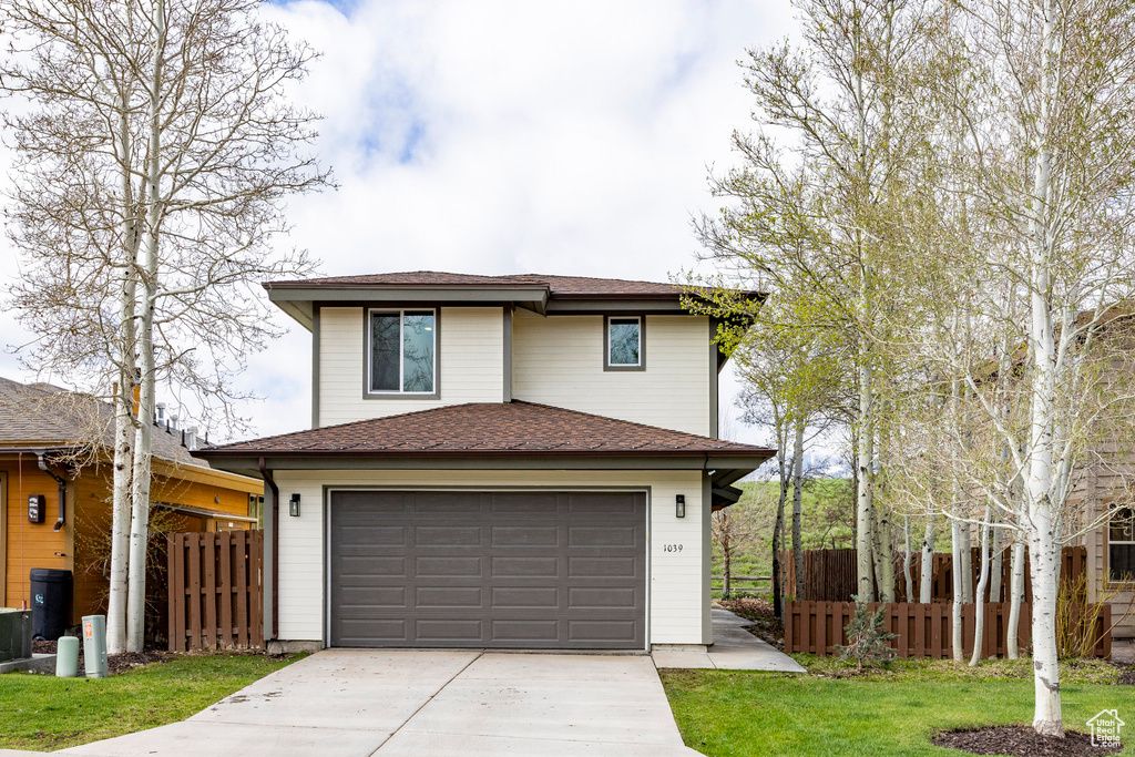 View of front of home featuring concrete driveway, an attached garage, and a shingled roof