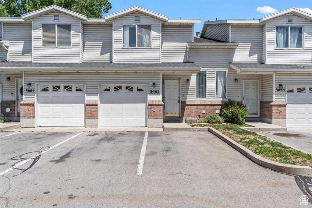 Multi unit property with brick siding, an attached garage, and driveway