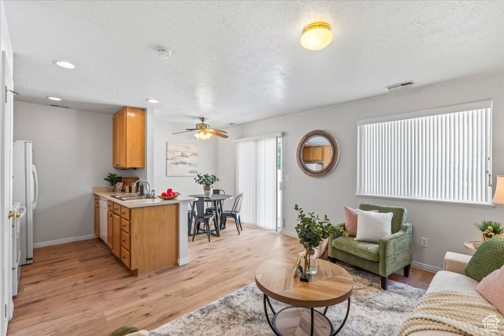 Living area with a ceiling fan, light wood-style flooring, a textured ceiling, baseboards, and recessed lighting
