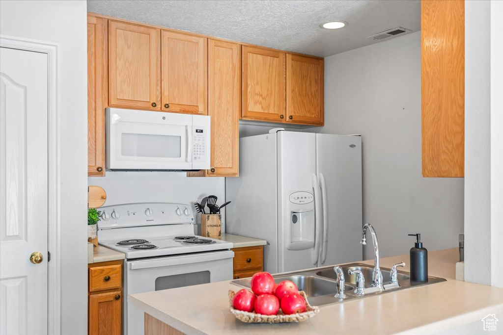 Kitchen featuring white appliances, light countertops, recessed lighting, and a sink
