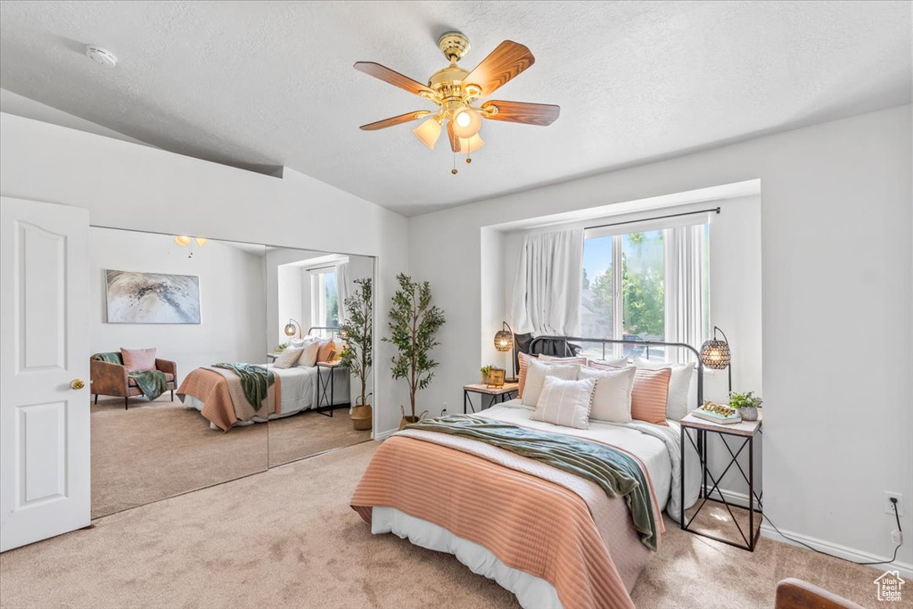 Carpeted bedroom featuring lofted ceiling and ceiling fan