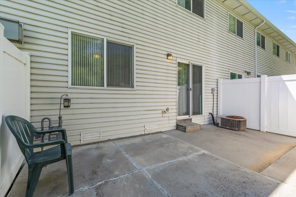 Back of property with a patio area, fence, and central AC
