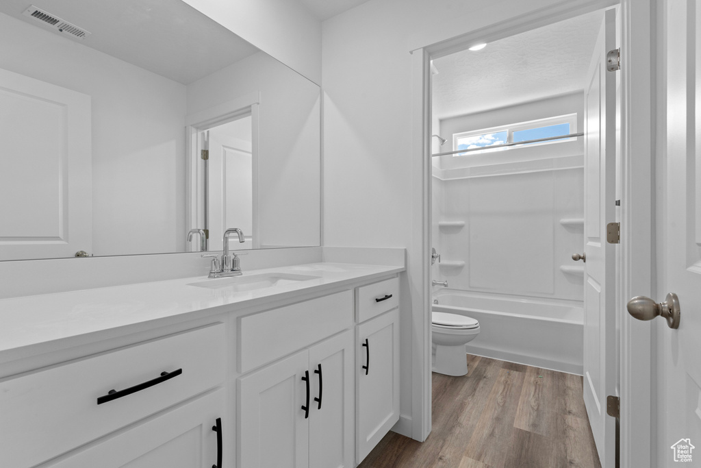 Full bathroom featuring wood finished floors, toilet, vanity, and shower / tub combination