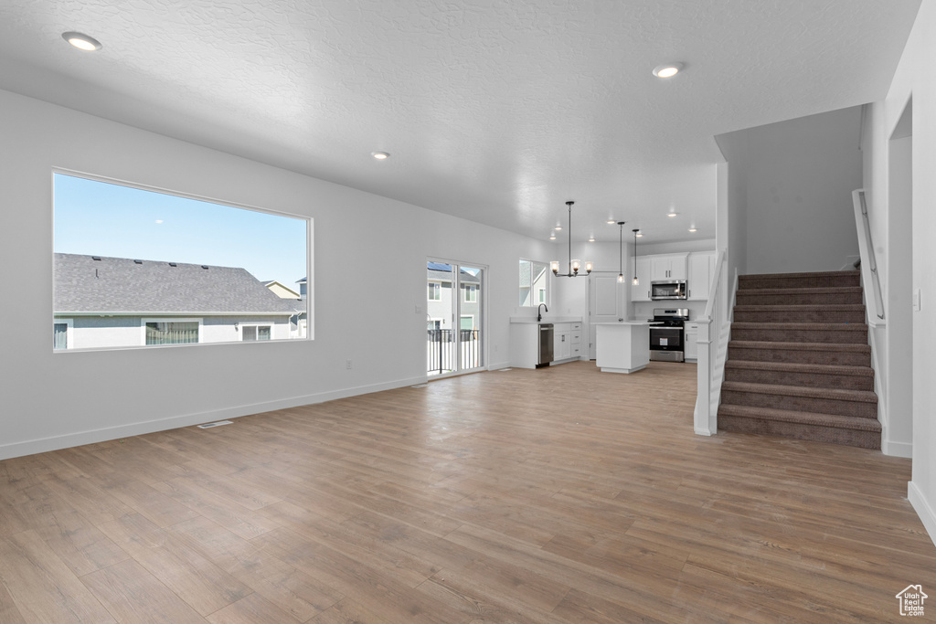 Unfurnished living room with light wood-type flooring, stairway, recessed lighting, and baseboards