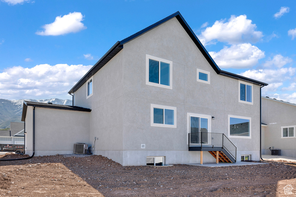 Back of property with central air condition unit and stucco siding