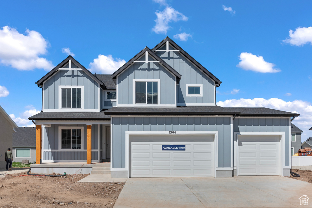 View of front of house with covered porch, driveway, board and batten siding, and a garage