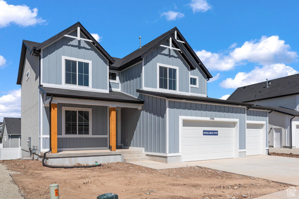 View of front of property with covered porch, driveway, board and batten siding, and an attached garage