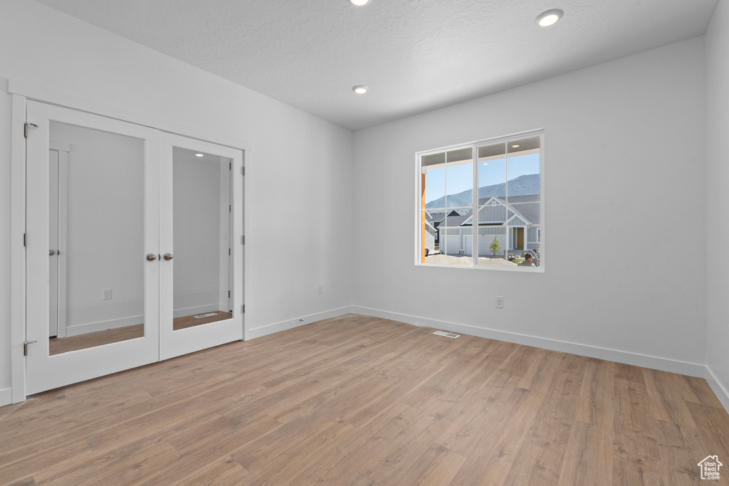 Spare room featuring light wood-type flooring, french doors, recessed lighting, and baseboards