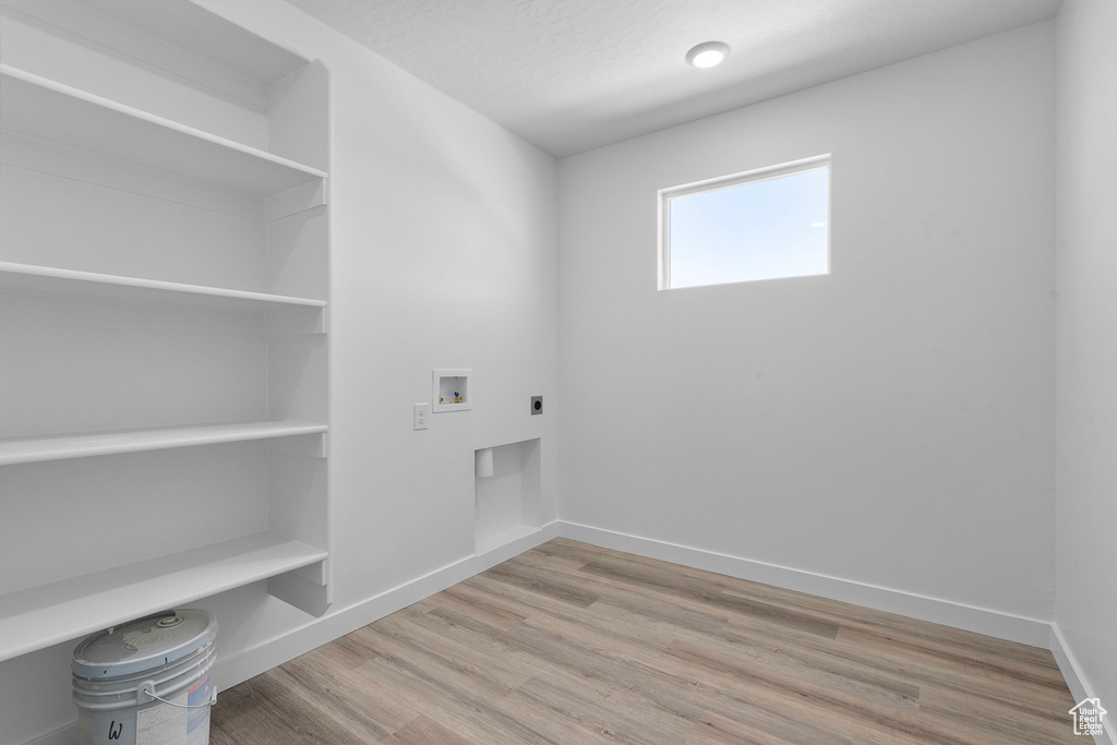 Laundry room with hookup for an electric dryer, hookup for a washing machine, baseboards, and wood finished floors