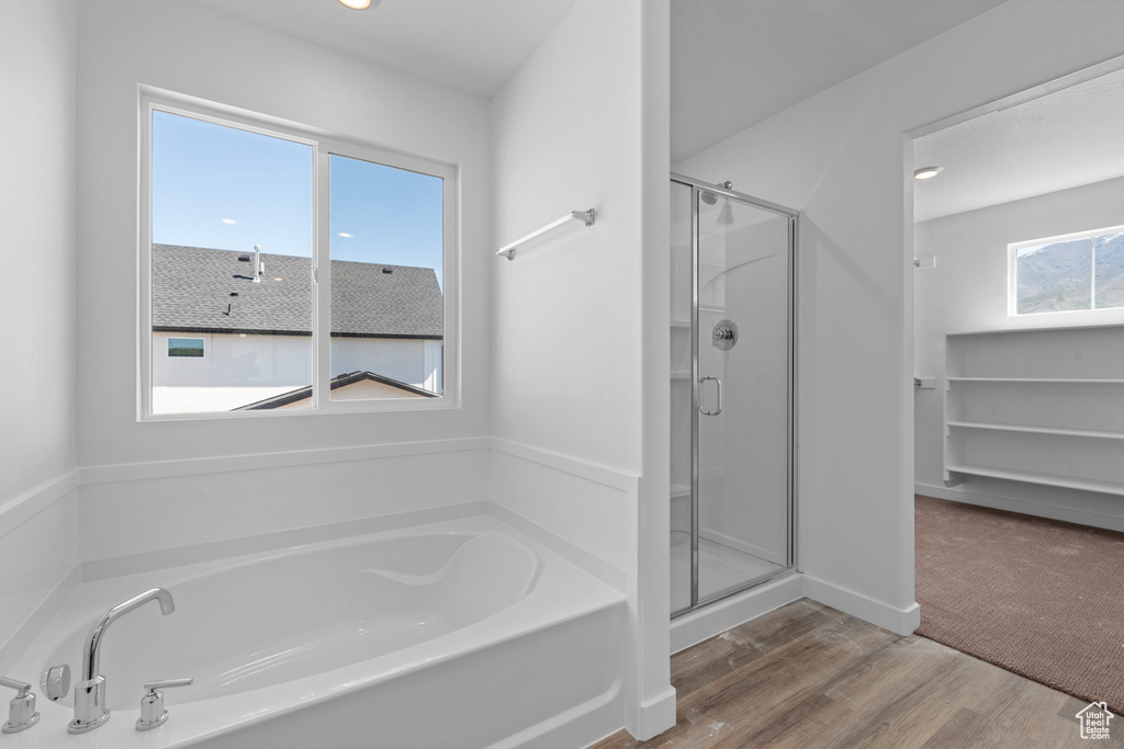 Full bathroom with a stall shower, a bath, wood finished floors, and recessed lighting