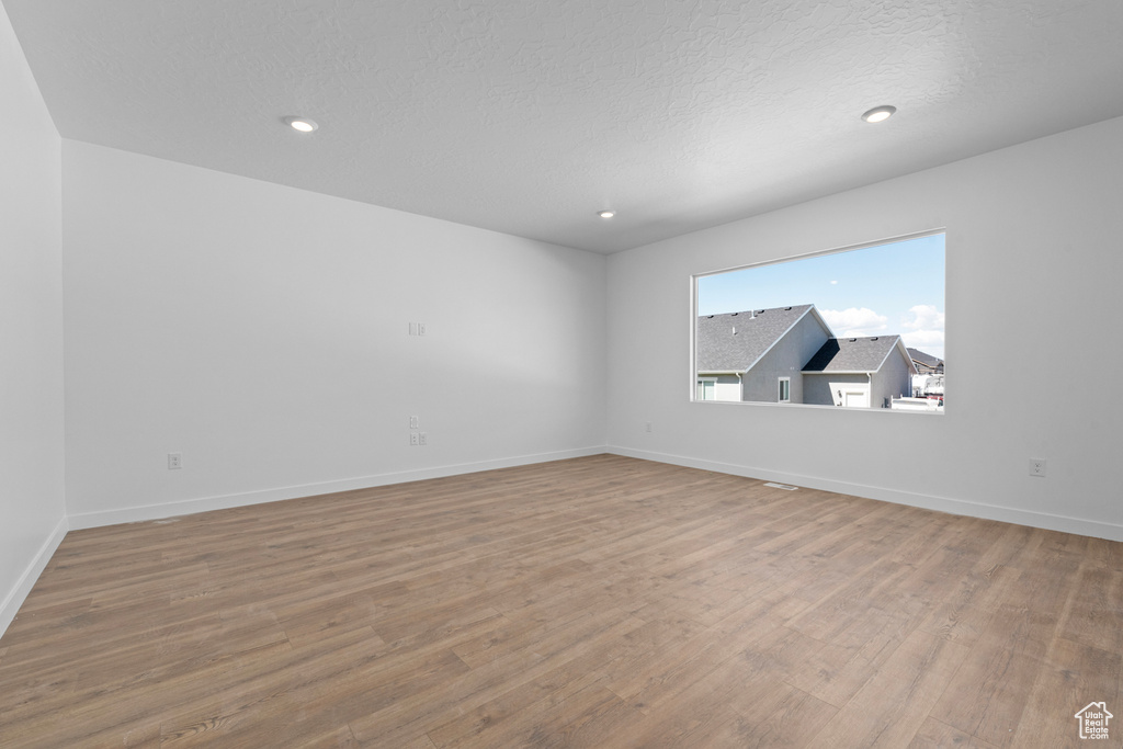Empty room featuring wood finished floors, baseboards, recessed lighting, and a textured ceiling