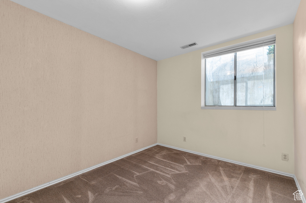 Spare room featuring carpet flooring and baseboards