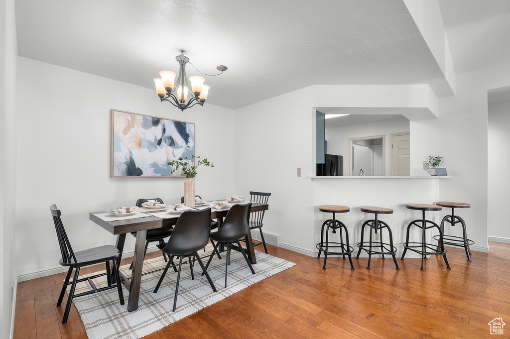 Dining room with wood-type flooring, a chandelier, and baseboards