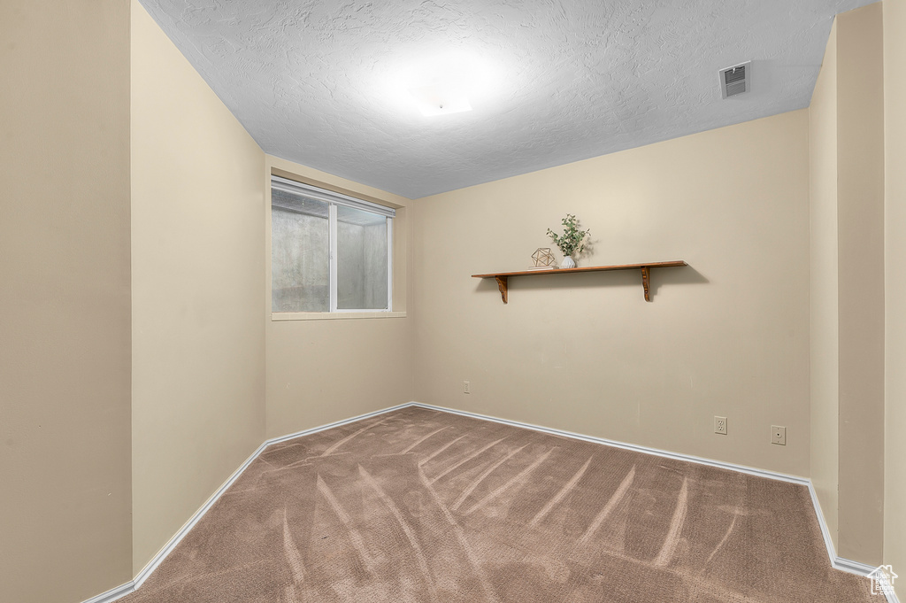 Unfurnished room featuring carpet floors, baseboards, and a textured ceiling