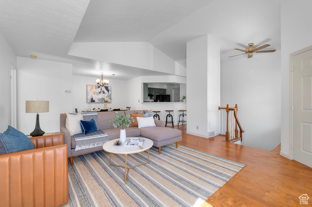 Living area with wood finished floors, a chandelier, a ceiling fan, and vaulted ceiling