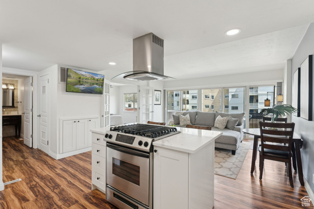 Kitchen with stainless steel range with gas cooktop, range hood, wood finished floors, a kitchen island, and recessed lighting