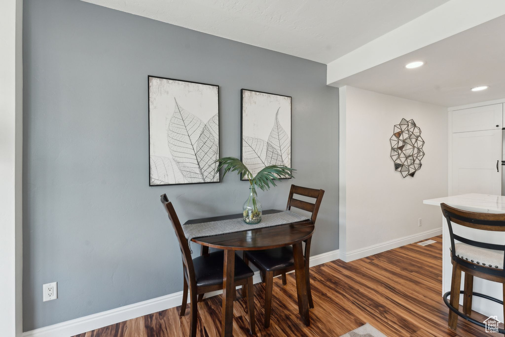 Dining room with dark wood-type flooring, baseboards, and recessed lighting