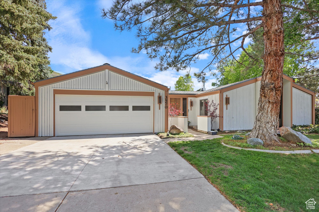 View of front facade with concrete driveway, an attached garage, and a front yard