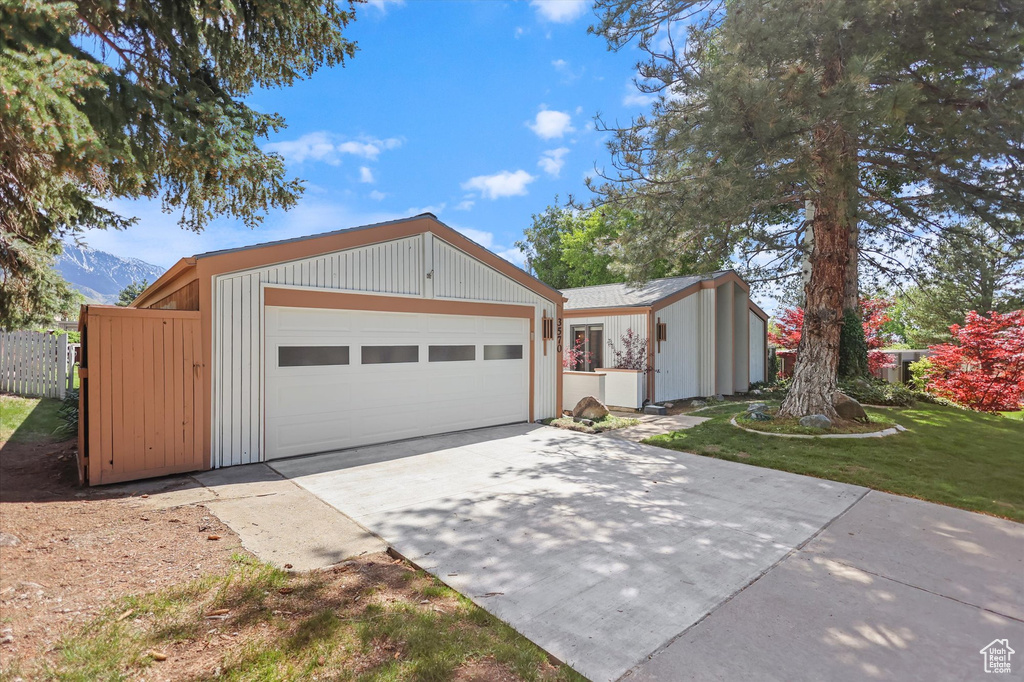 View of front of home with concrete driveway, a garage, fence, and a mountain view