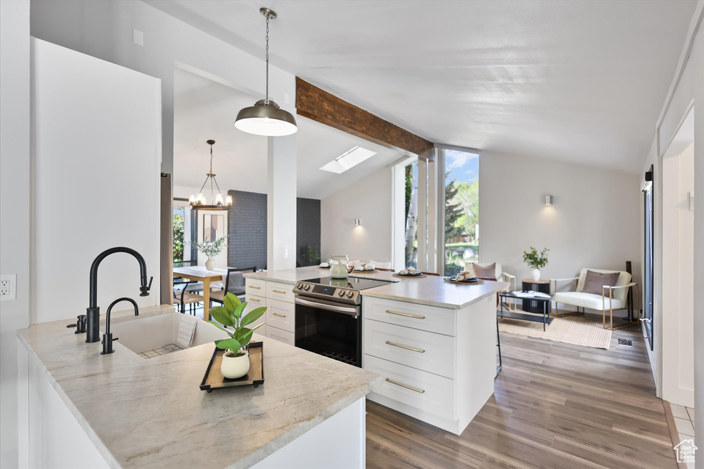 Kitchen featuring stainless steel electric range oven, white cabinetry, a chandelier, wood finished floors, and a sink