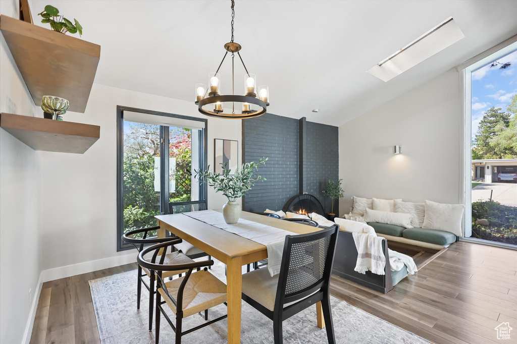 Dining area featuring vaulted ceiling, wood finished floors, a chandelier, a wood stove, and baseboards