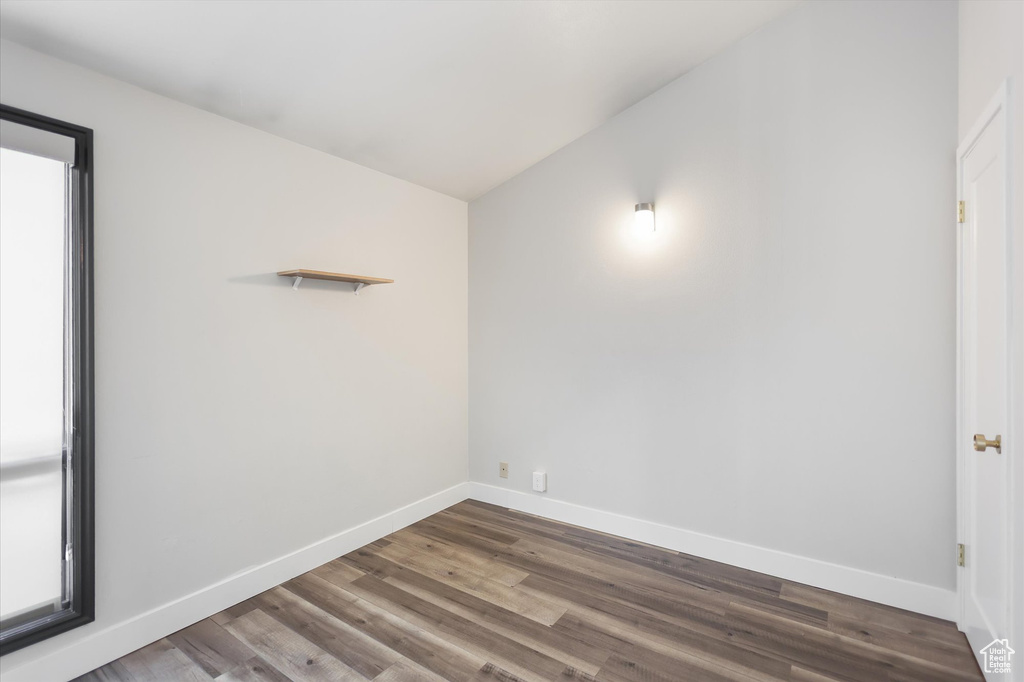Empty room with baseboards, wood finished floors, and vaulted ceiling