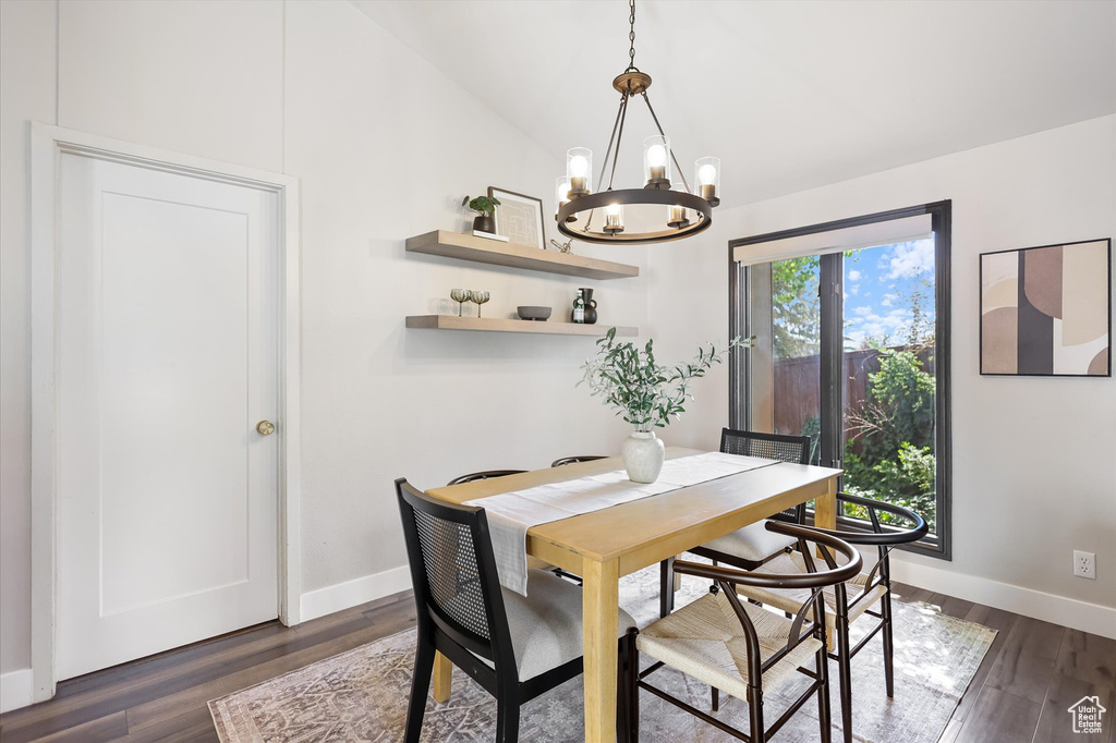 Dining room featuring a chandelier, baseboards, dark wood-style floors, and vaulted ceiling