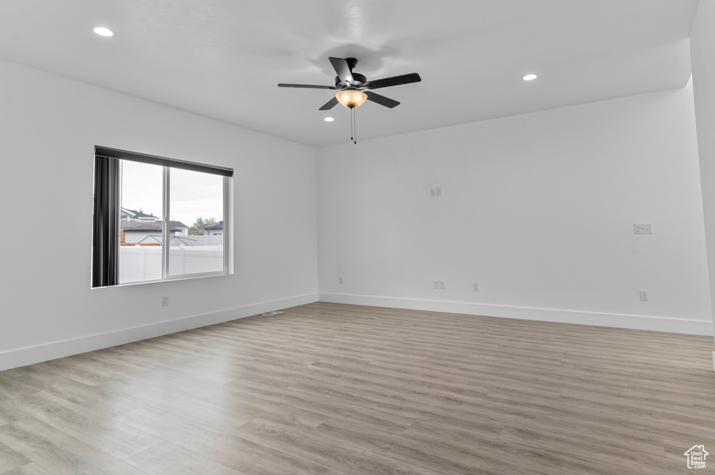 Empty room featuring ceiling fan, light wood-style flooring, baseboards, and recessed lighting
