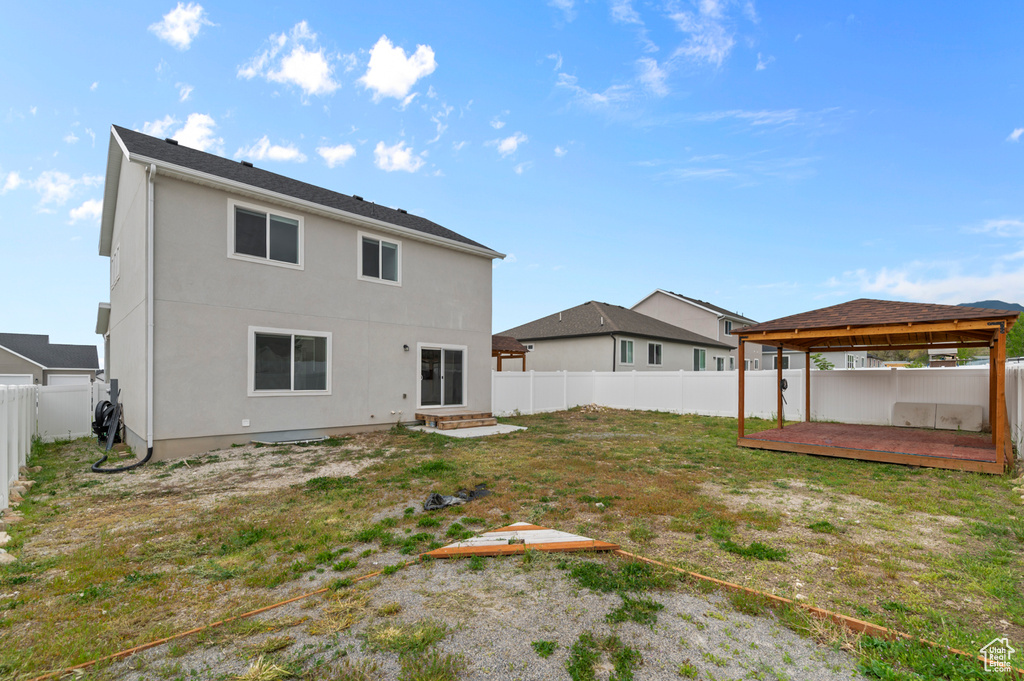 Rear view of house with a gazebo, a fenced backyard, stucco siding, a wooden deck, and entry steps