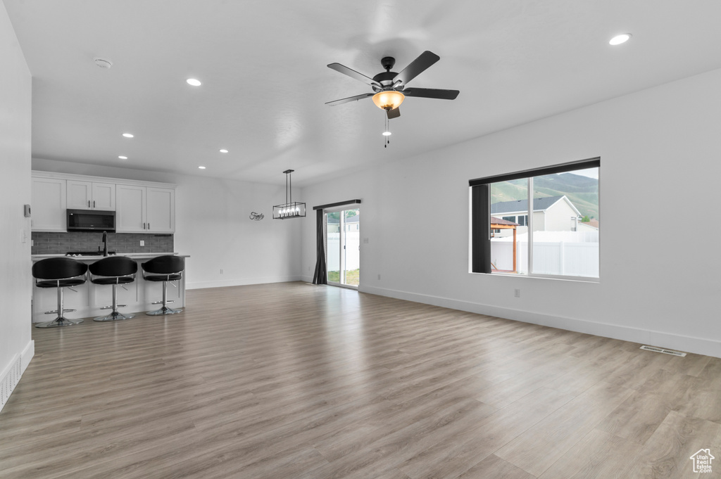 Unfurnished living room with recessed lighting, light wood-type flooring, a ceiling fan, baseboards, and a sink
