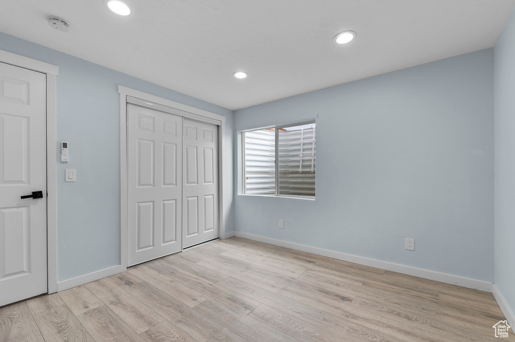 Unfurnished bedroom with light wood-style floors, baseboards, recessed lighting, and a closet