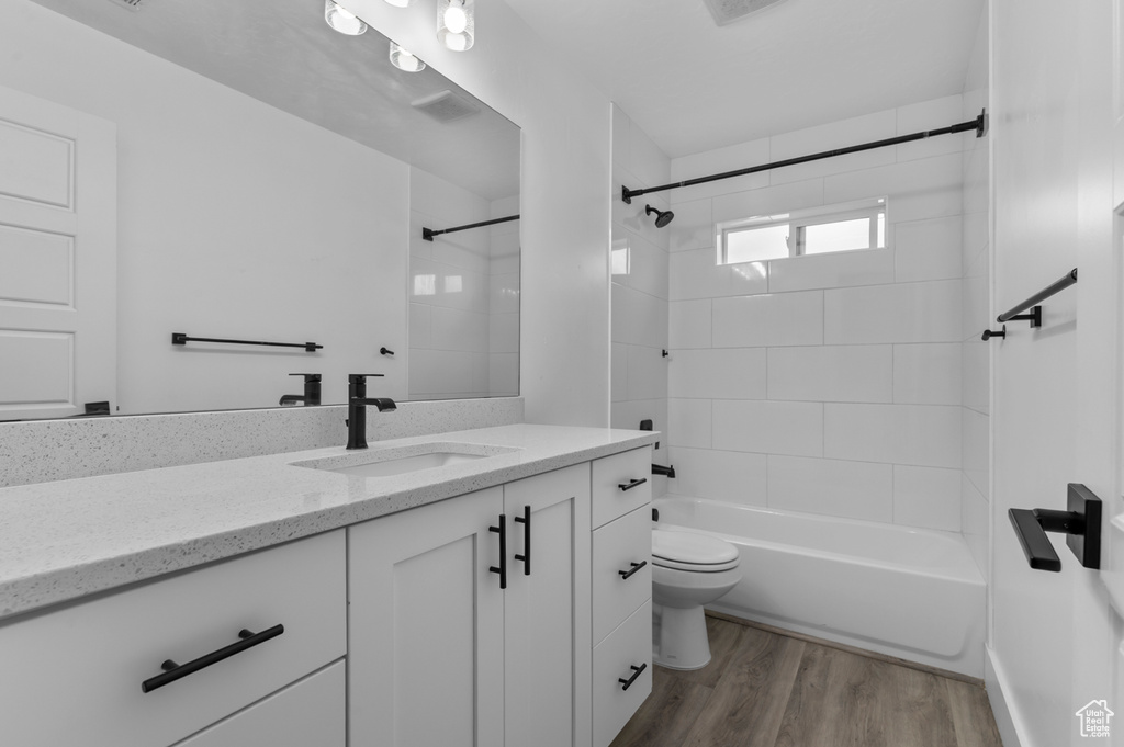 Full bath featuring wood finished floors, toilet, vanity, and shower / washtub combination