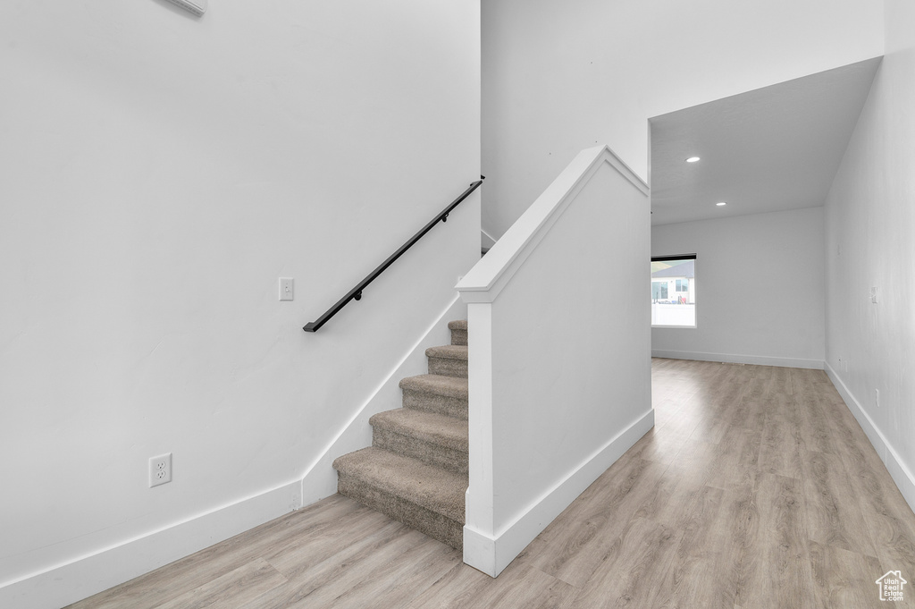 Stairs with wood finished floors, recessed lighting, and baseboards