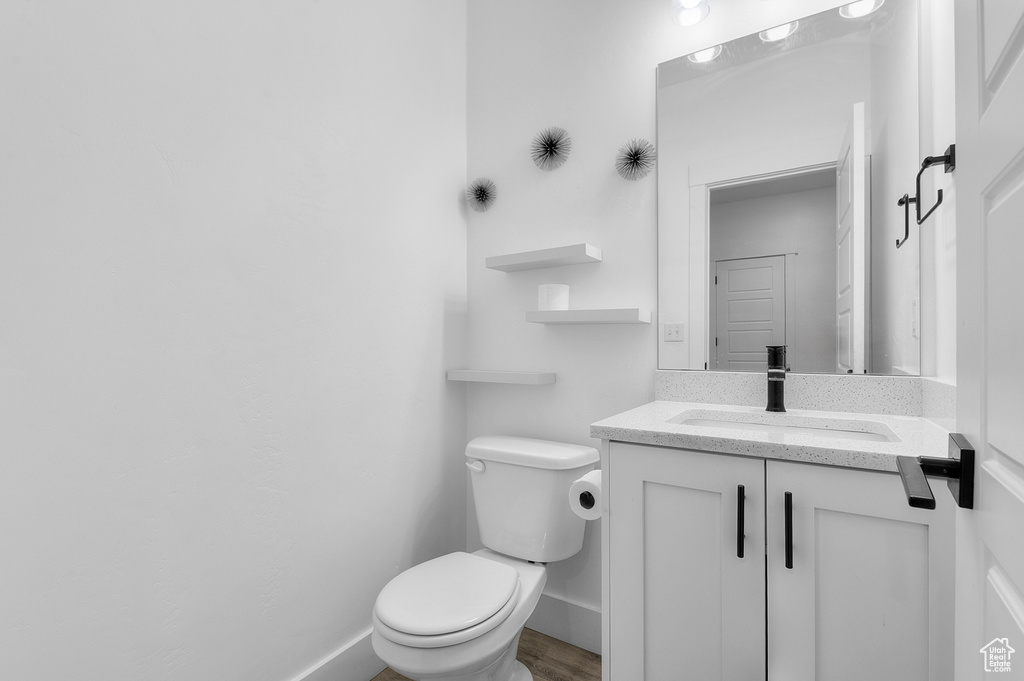 Bathroom with toilet, vanity, baseboards, and wood finished floors