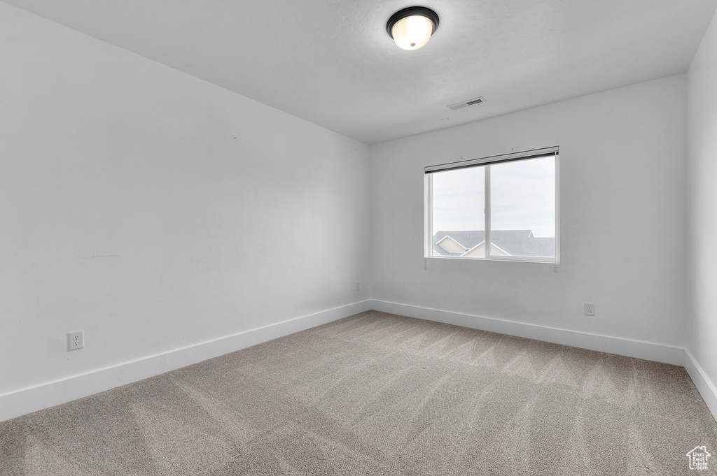 Spare room with baseboards and light carpet
