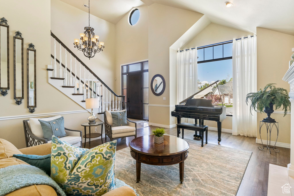 Sitting room featuring plenty of natural light, a chandelier, wood finished floors, stairs, and high vaulted ceiling