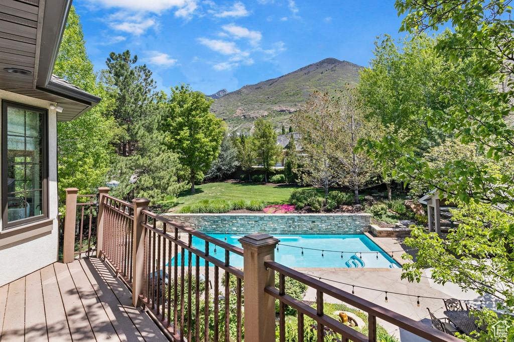 Outdoor pool featuring a deck with mountain view and a lawn