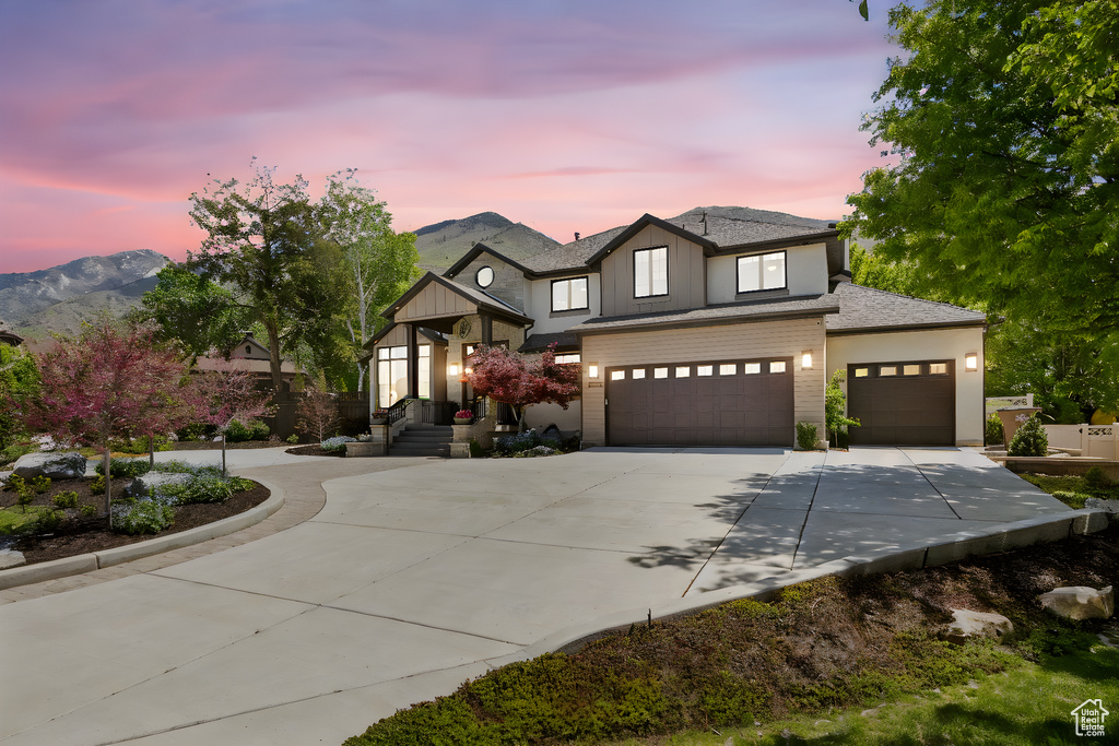 View of front of home with concrete driveway, an attached garage, a mountain view, and a shingled roof