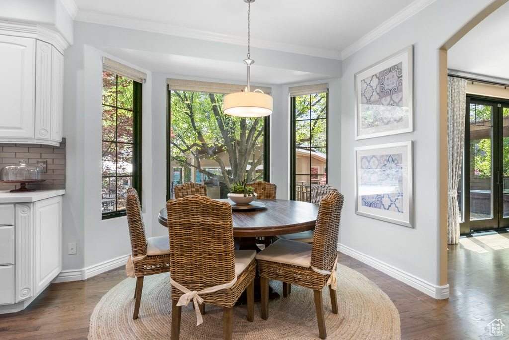 Dining room featuring baseboards, crown molding, and dark wood-type flooring