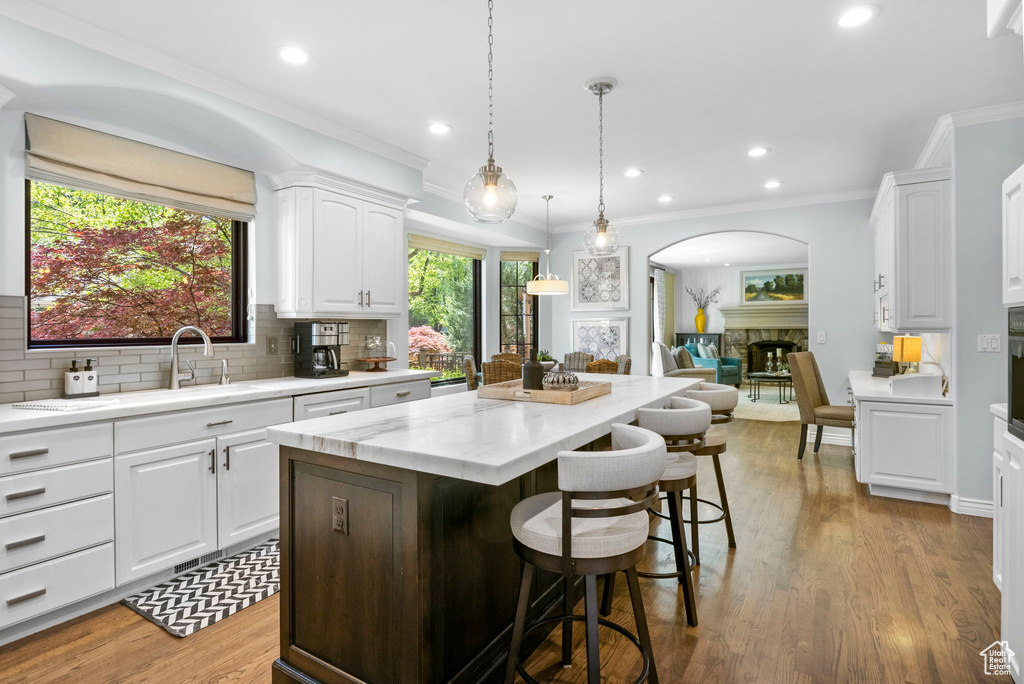 Kitchen featuring arched walkways, a center island, tasteful backsplash, white cabinetry, and recessed lighting