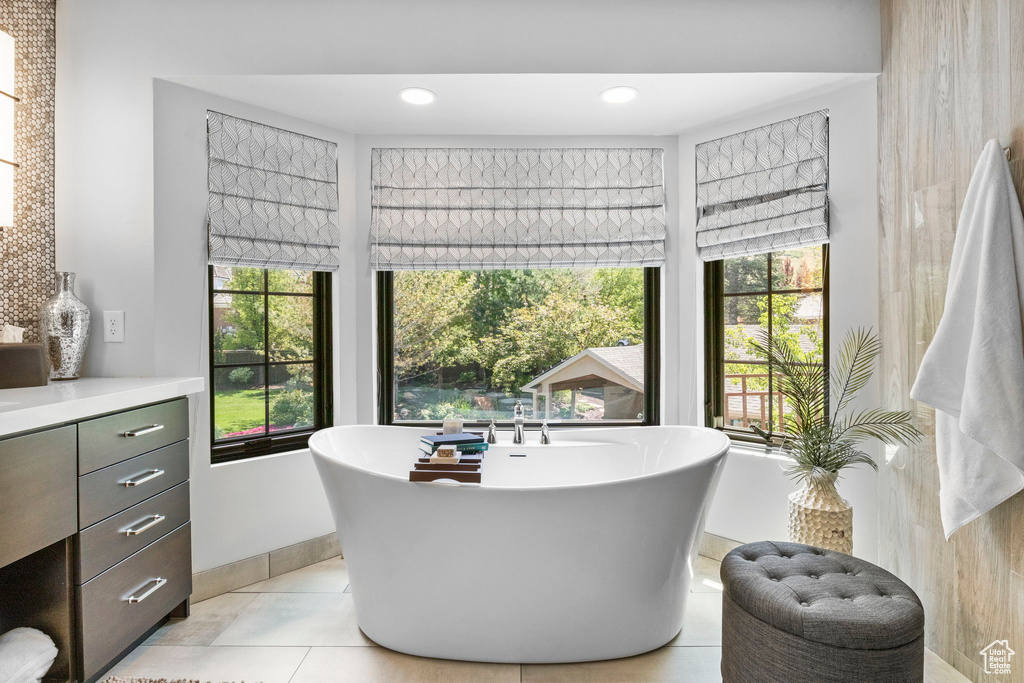 Full bathroom featuring a soaking tub, vanity, tile patterned floors, and baseboards